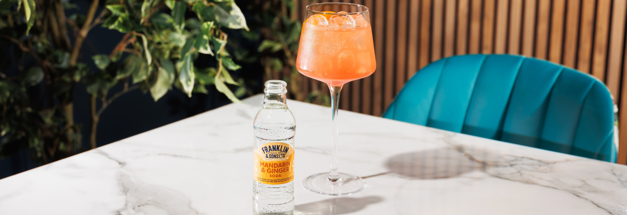 Mandarin and ginger soda next to a orange spritz cocktail with a floral background | Franklin & Sons