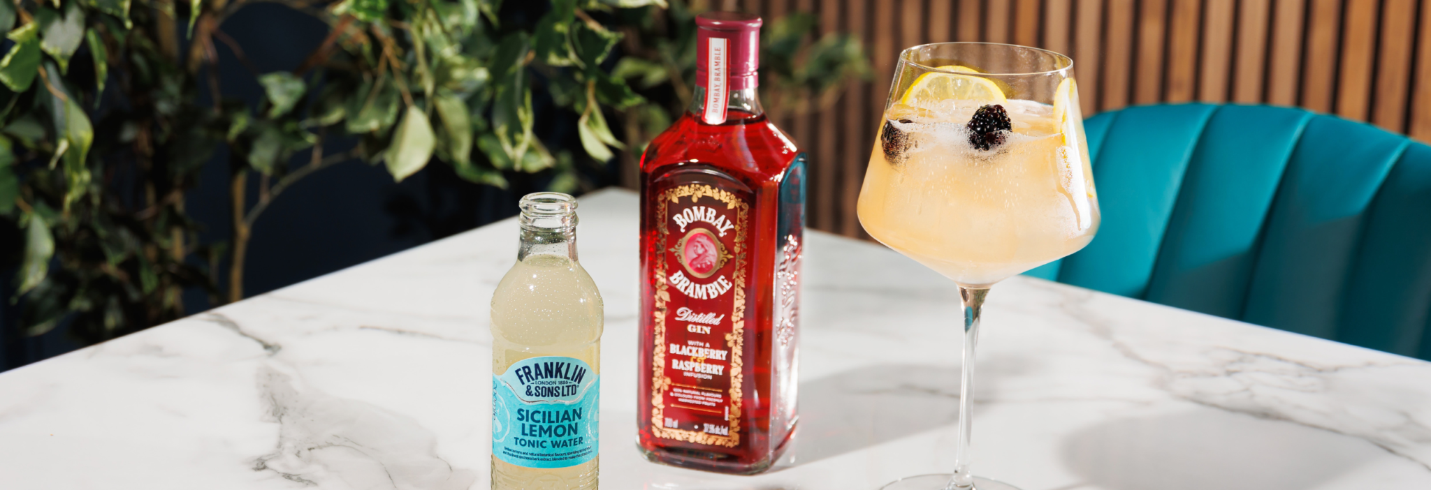 Sicilian Lemon Tonic Water next to bombay bramble gin and a wine glass with a cocktail in - garnished with blackberries and lemon peel | Franklin & Sons