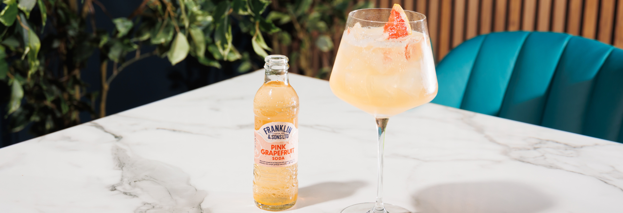 Pink Grapefruit Soda next to a cocktail with grapefruit peel as the garnish | Franklin & Sons